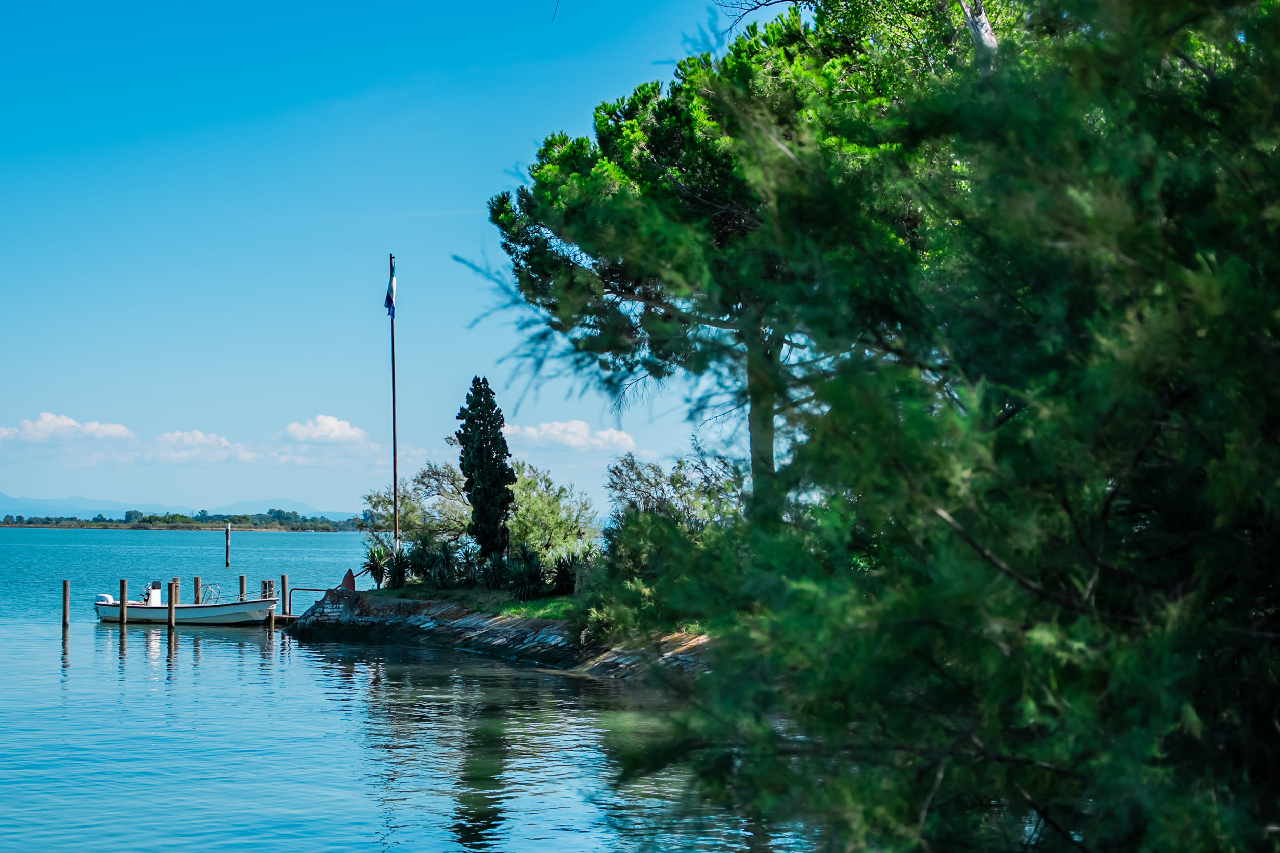 Veduta dall'argine dell'approdo di Punta Marana. La bandiera è issata e c'è una barca attraccata.